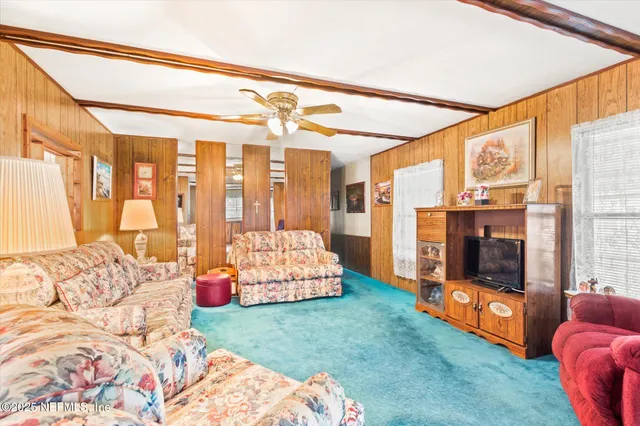 a living room with a bed furniture and next to a window