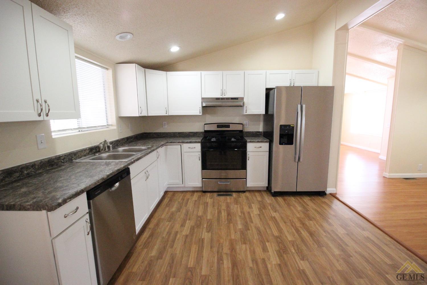 Undisclosed Address Bakersfield, CA 93308 - Photo 11 of 26 a kitchen with a refrigerator a sink and wooden floor
