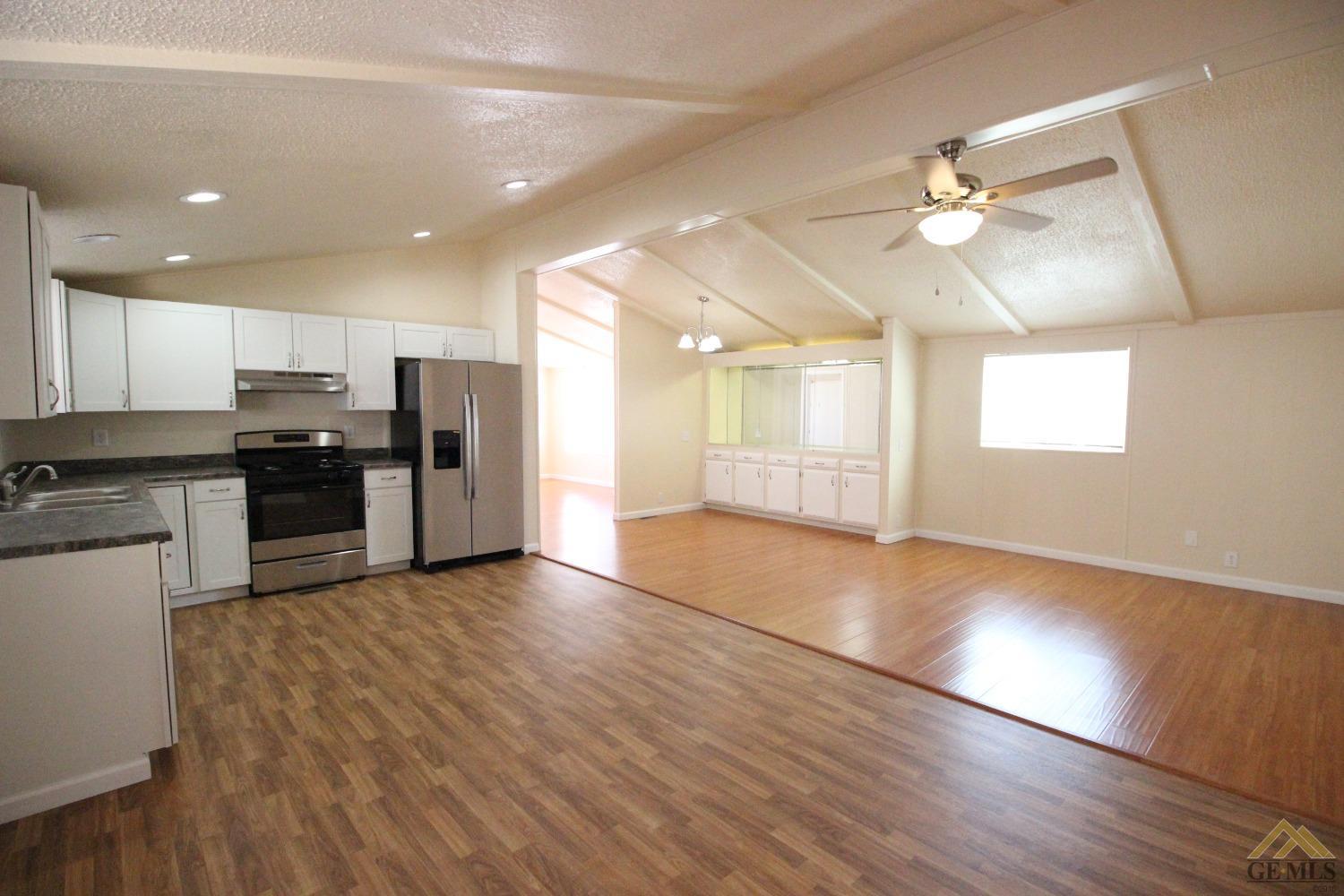 Undisclosed Address Bakersfield, CA 93308 - Photo 10 of 26 an open kitchen with kitchen island wooden floors appliances and cabinets