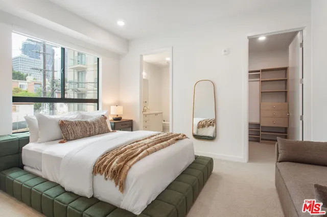 a bedroom with a bed couch and large window