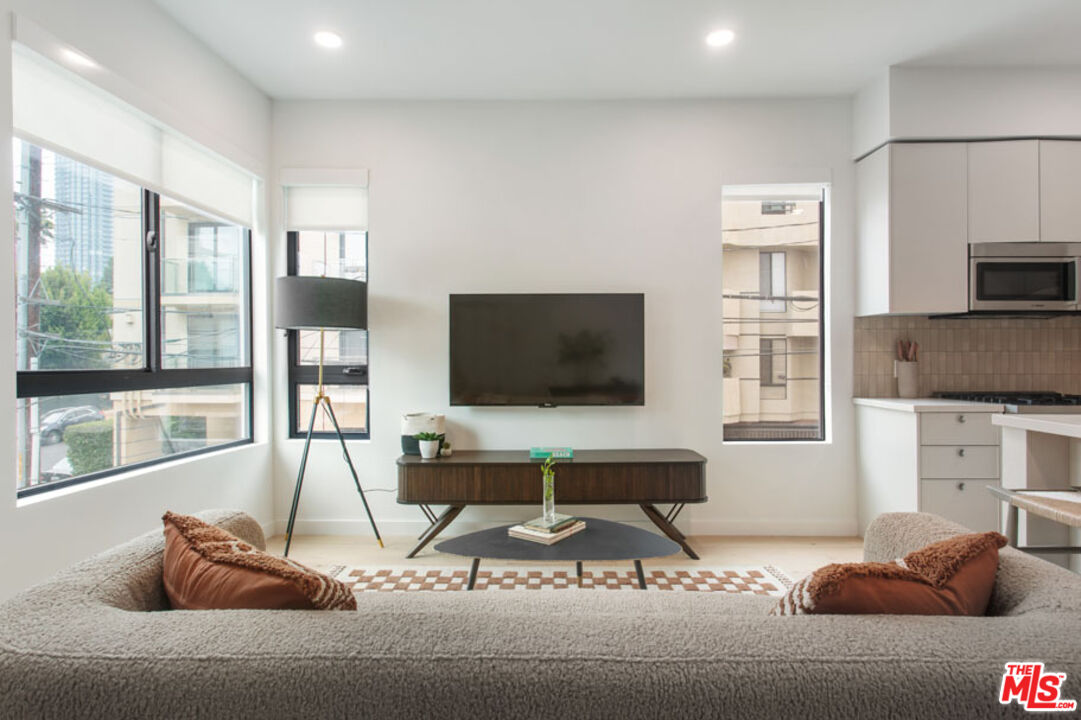 10310 Santa Monica Boulevard, Unit 216 Los Angeles, CA 90025 - Photo 9 of 38 a living room with furniture a flat screen tv and a large window