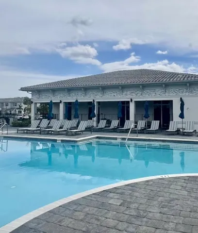 a view of a white house with a potted plant and palm trees