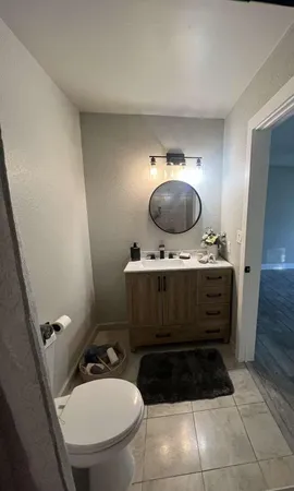 a bathroom with a toilet mirror vanity and sink