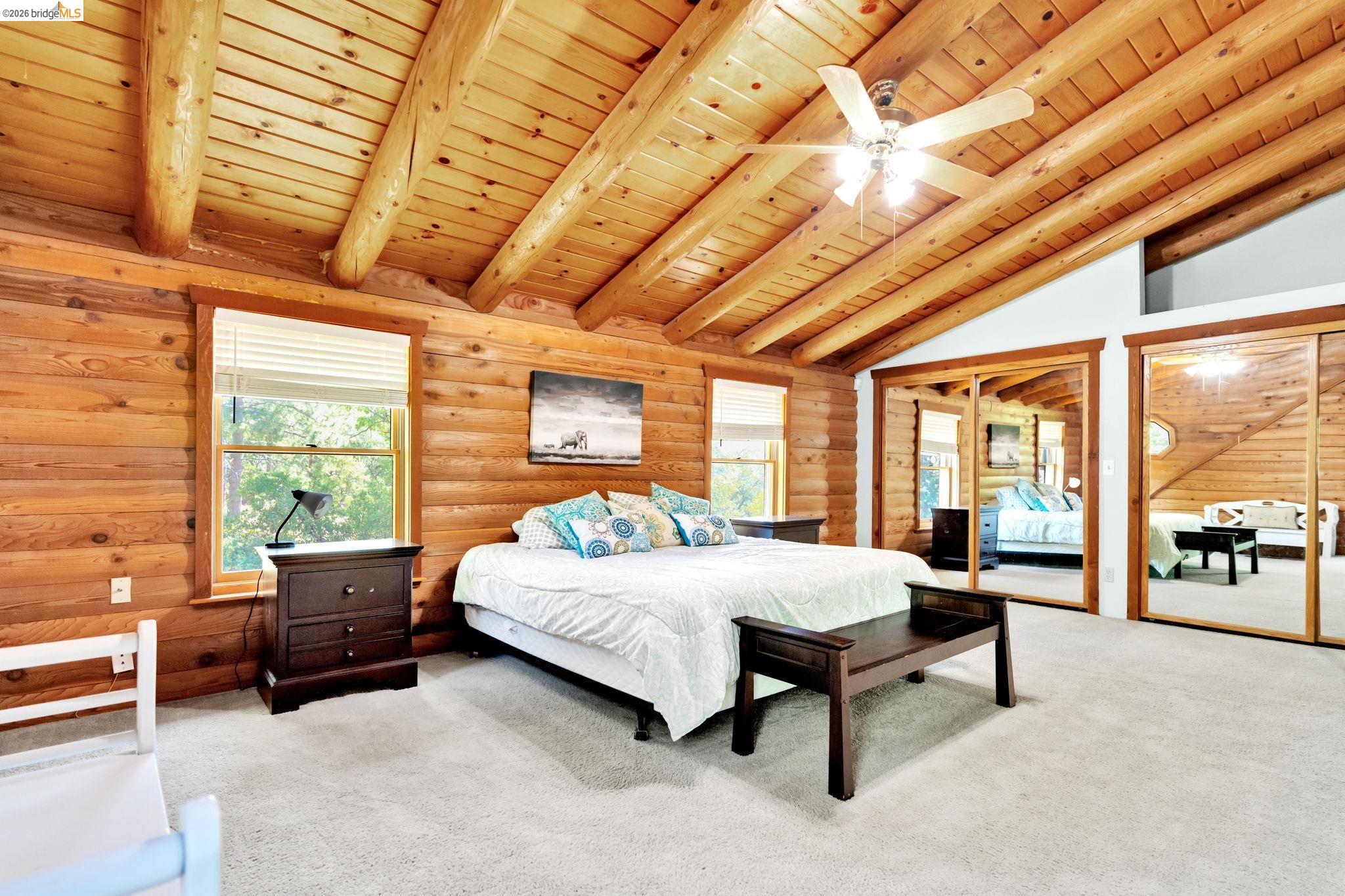 14799 Big Hill Road Sonora, CA 95370 - Photo 30 of 60 Carpeted bedroom with wooden ceiling, log walls, multiple closets, a ceiling fan, and vaulted ceiling with beams