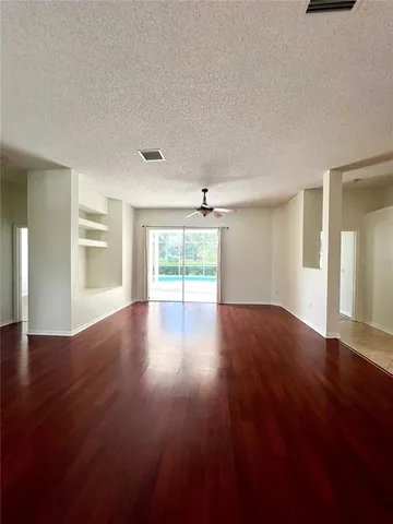 a view of empty room with wooden floor and fan