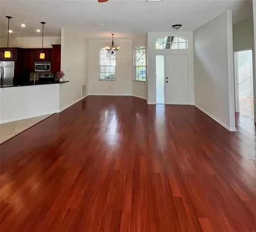 a view of a big room with wooden floor and windows
