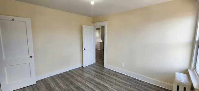 a view of an empty room with wooden floor and closet