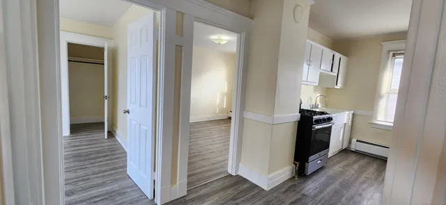 a view of a kitchen from a hallway with wooden floor