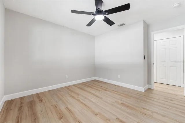 an empty room with wooden floor and a ceiling fan