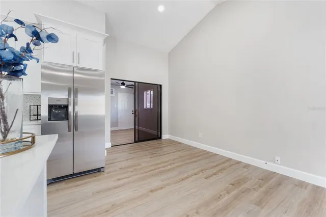 a view of a kitchen with wooden floor electronic appliances and a window
