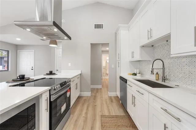 a kitchen with granite countertop a sink stainless steel appliances and white cabinets