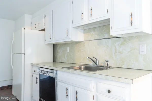 a kitchen with stainless steel appliances granite countertop a sink a refrigerator and white cabinets