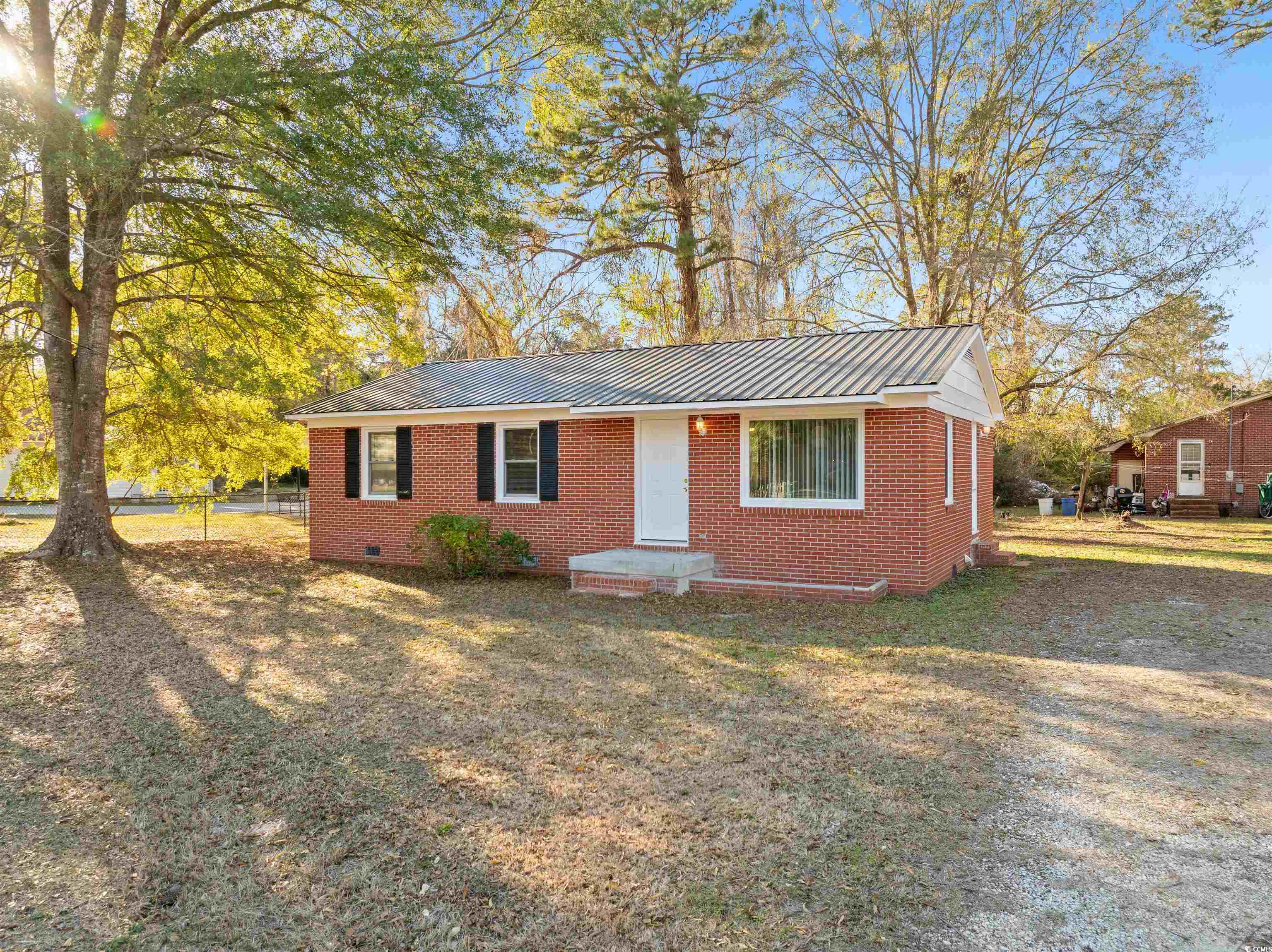 Single story home featuring a metal roof, brick siding, crawl space, and a front yard