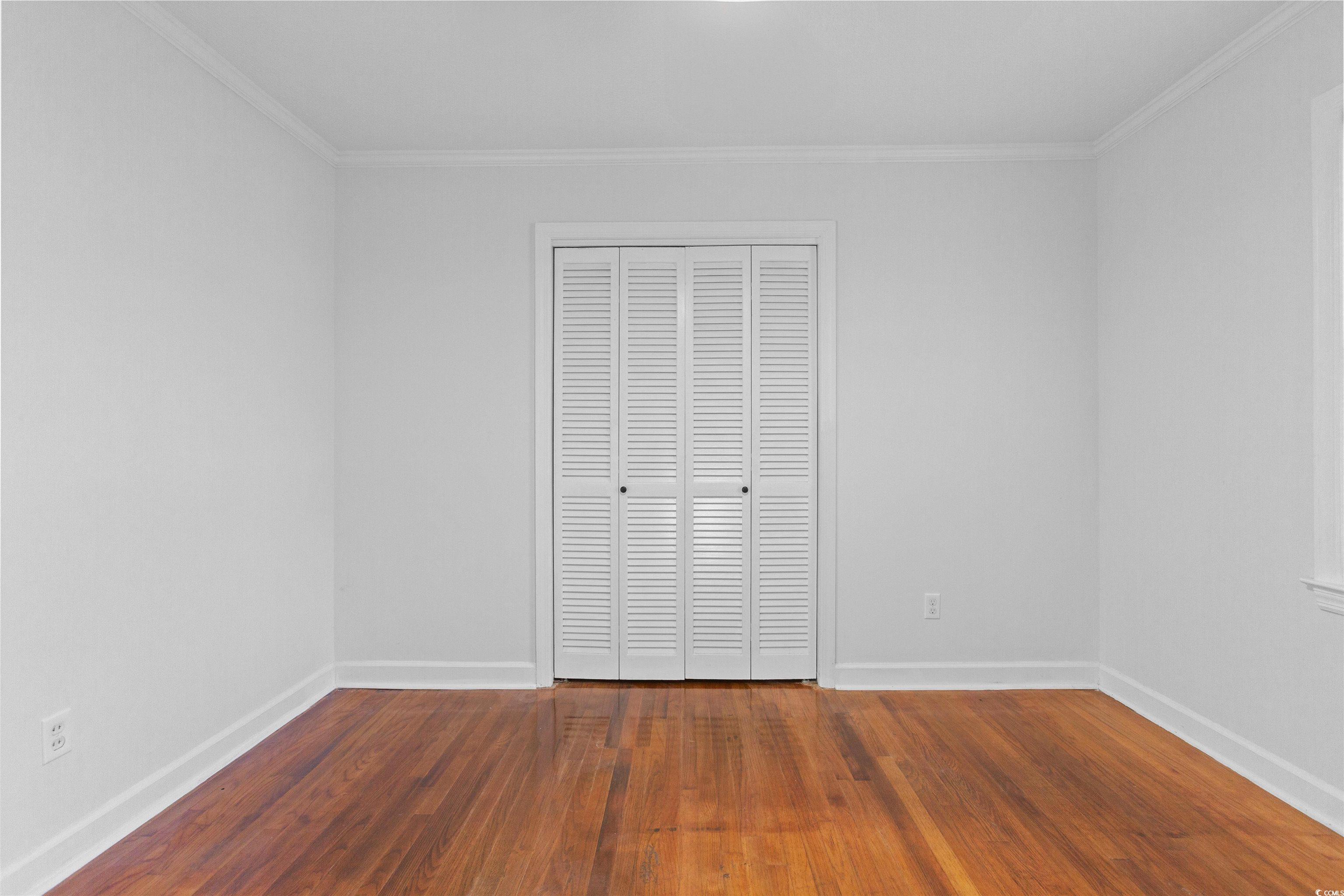 139 State Rd S-22-496 Andrews, SC 29510 - Photo 12 of 20 Unfurnished bedroom with ornamental molding, dark wood-style floors, and a closet