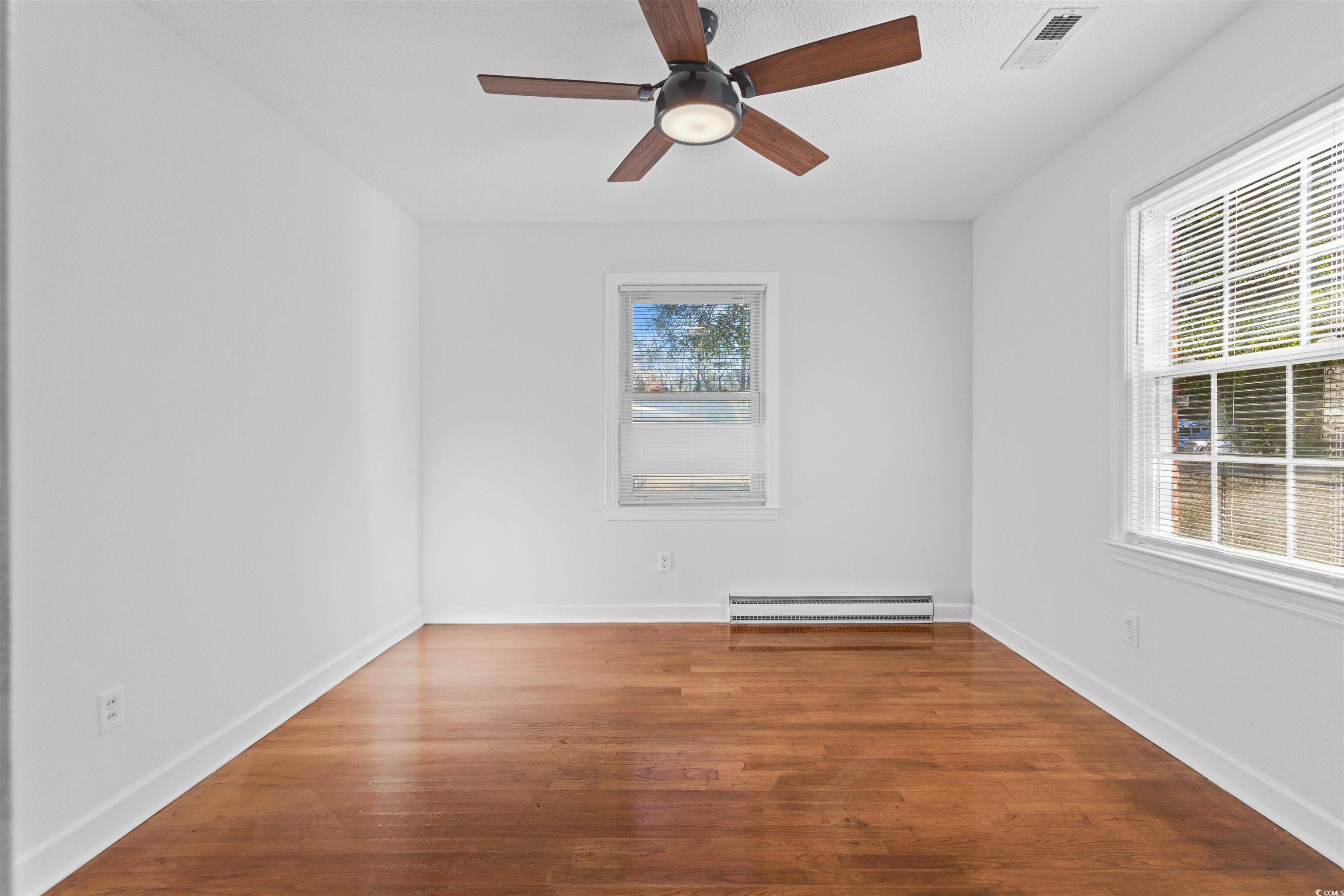 139 State Rd S-22-496 Andrews, SC 29510 - Photo 14 of 20 Spare room featuring wood-type flooring, ceiling fan, and a baseboard heating unit