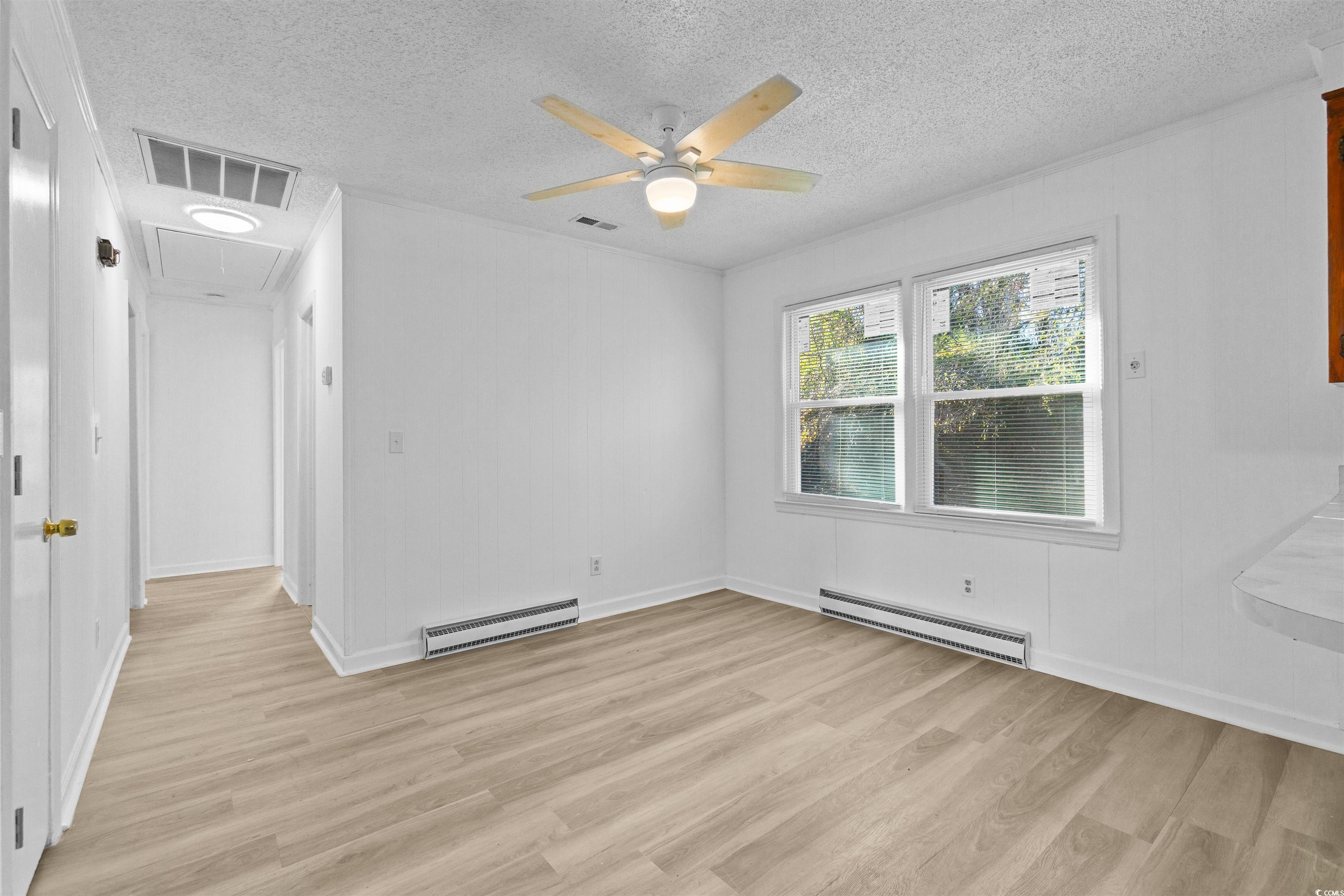 139 State Rd S-22-496 Andrews, SC 29510 - Photo 16 of 20 Spare room with attic access, a baseboard radiator, light wood finished floors, and a textured ceiling