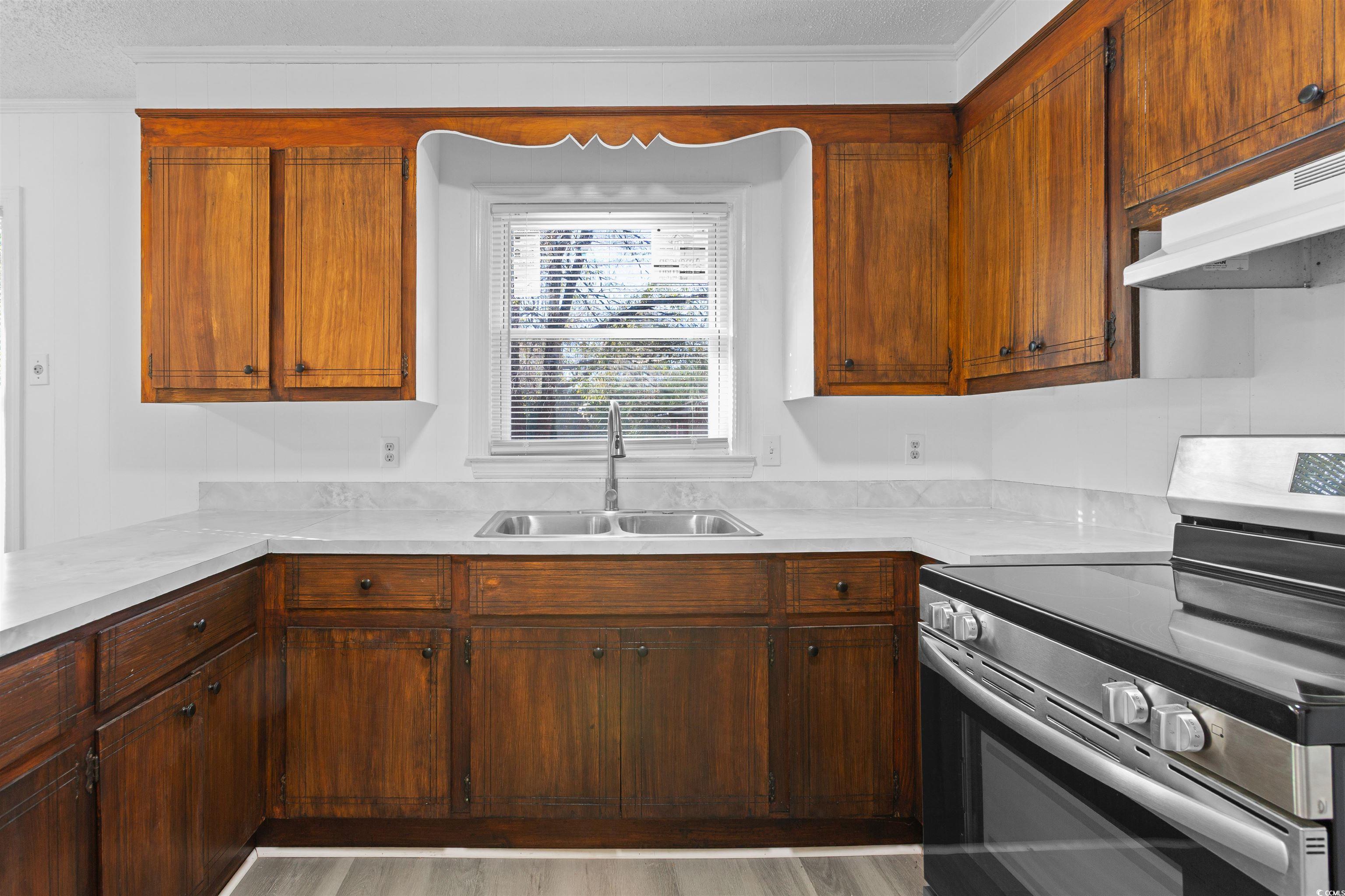 139 State Rd S-22-496 Andrews, SC 29510 - Photo 5 of 20 Kitchen featuring stainless steel electric range, light countertops, ornamental molding, under cabinet range hood, and light wood-style flooring