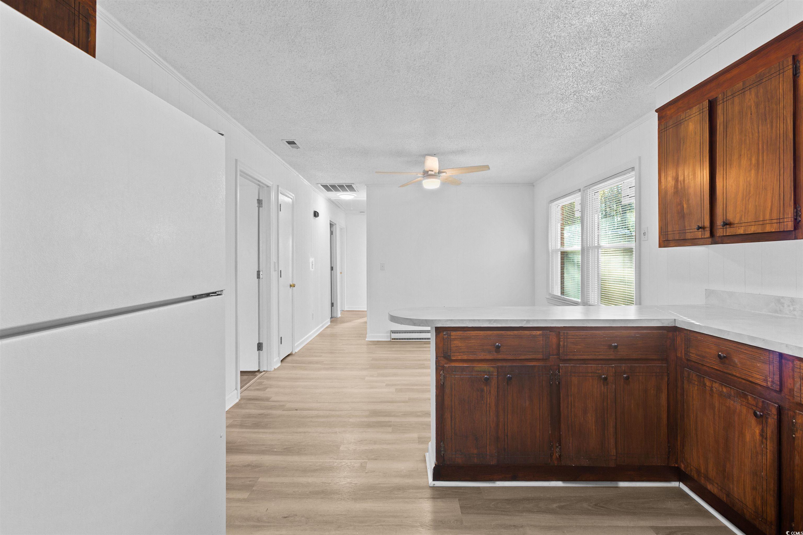 139 State Rd S-22-496 Andrews, SC 29510 - Photo 6 of 20 Kitchen featuring freestanding refrigerator, a peninsula, light countertops, a textured ceiling, and light wood-style flooring