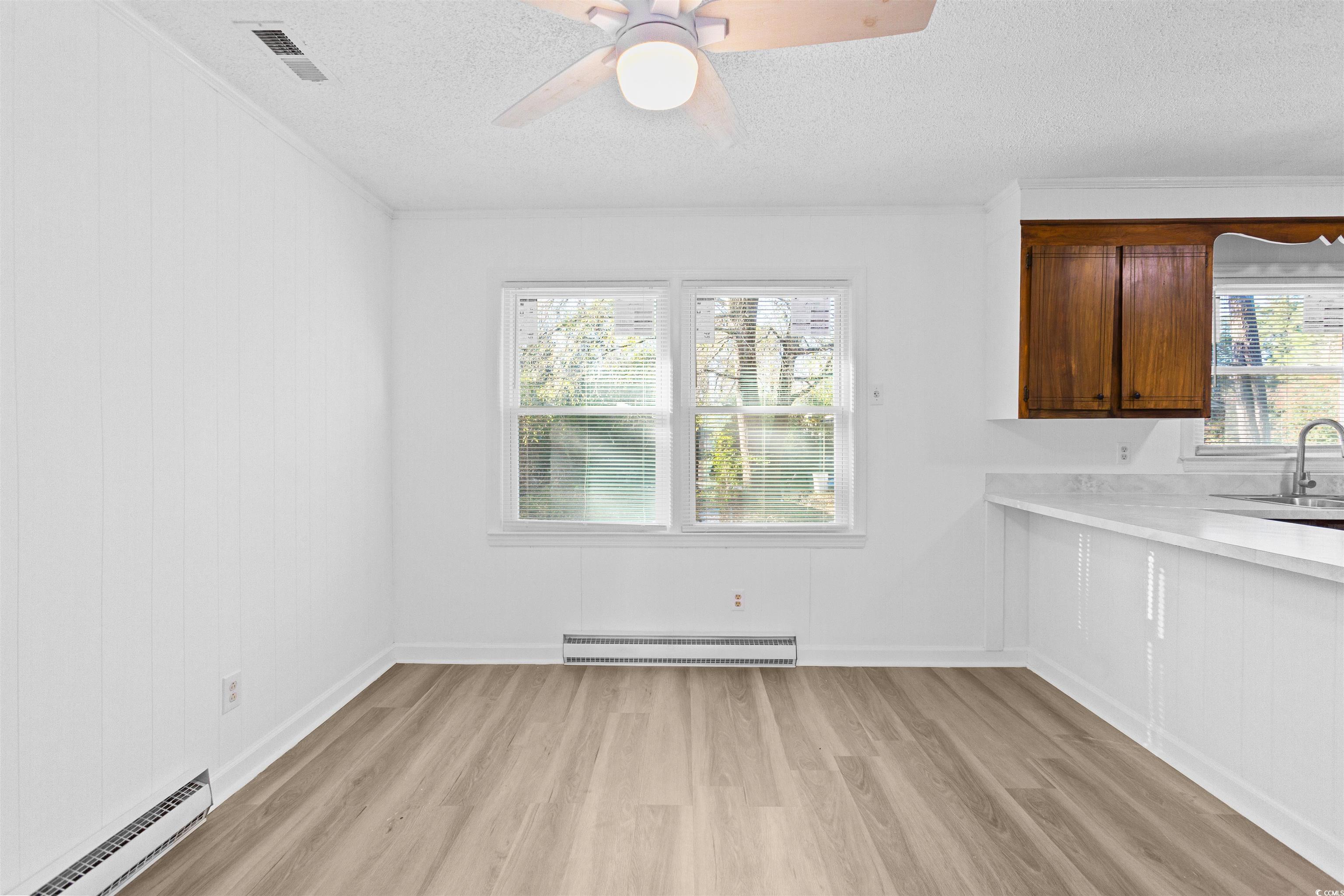 139 State Rd S-22-496 Andrews, SC 29510 - Photo 8 of 20 Unfurnished dining area featuring a baseboard radiator, a textured ceiling, light wood-style flooring, a ceiling fan, and a baseboard heating unit
