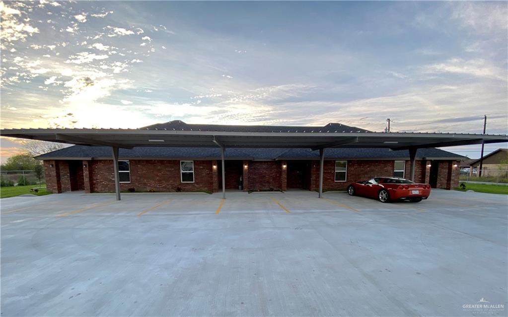 a view of a house with a barbeque and large trees