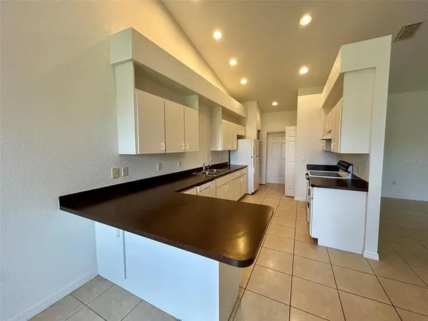 a kitchen with stainless steel appliances a refrigerator a stove top oven and white cabinets