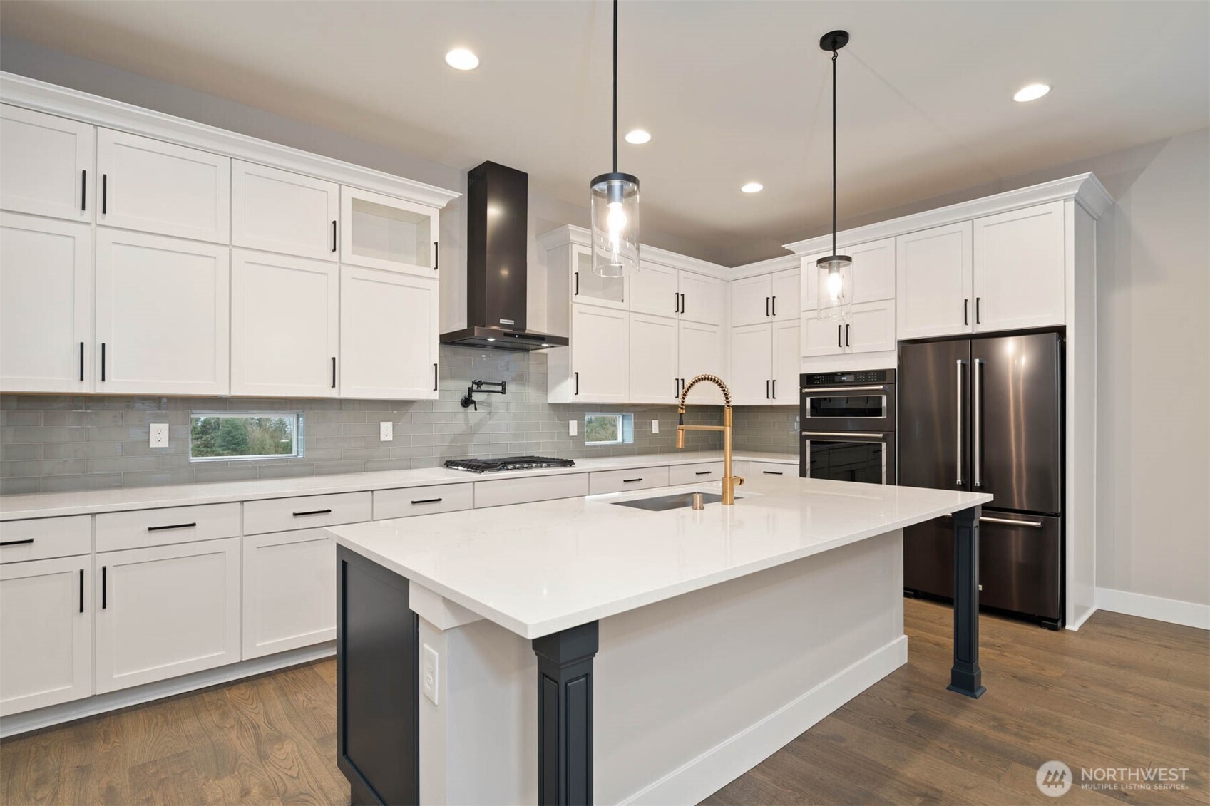 7560 South 130th Place Seattle, WA 98178 - Photo 25 of 27 a kitchen with a white center island a stove a refrigerator and white cabinets with wooden floor