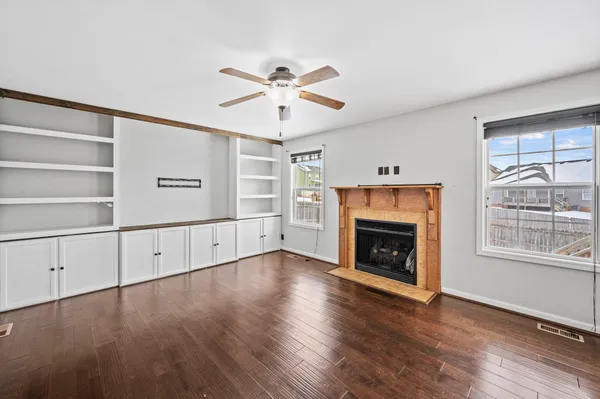 an empty room with windows fireplace and wooden floor
