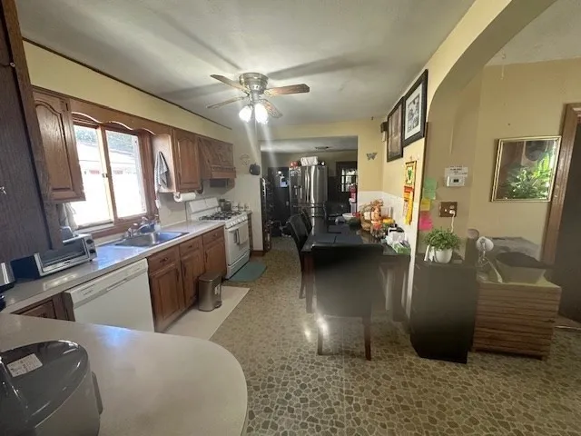 a living room with stainless steel appliances furniture a chandelier a fireplace and a view