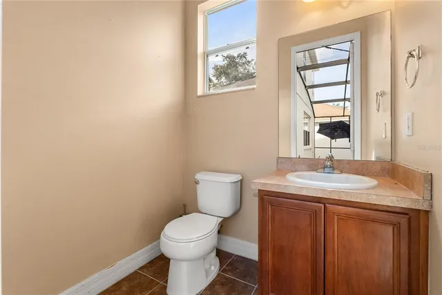 a bathroom with a granite countertop toilet a sink and a window