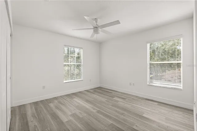 a view of an empty room with wooden floor and a window