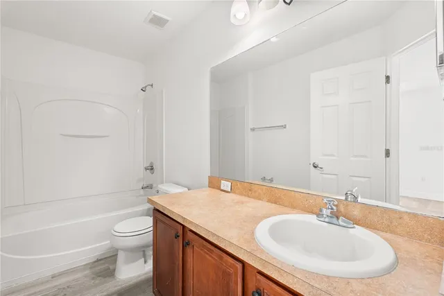 a bathroom with a granite countertop sink a toilet and bathtub