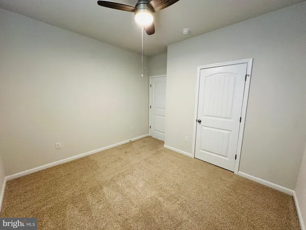 an empty room with a ceiling fan and entryway