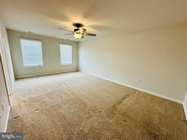 en empty room with windows and ceiling fan
