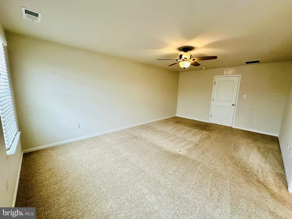 an empty room with a ceiling fan and a window