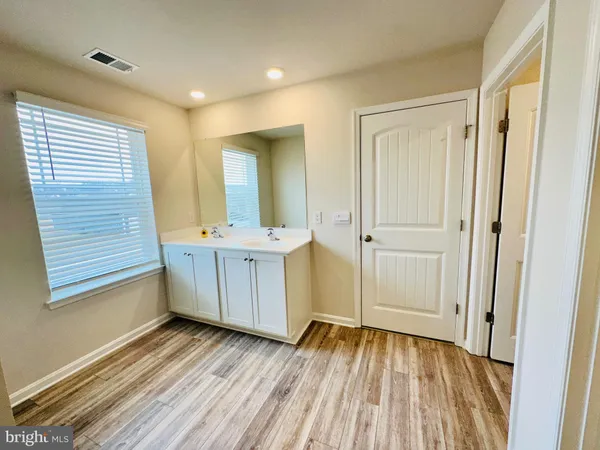 a view of a hallway with wooden floor and a bathroom