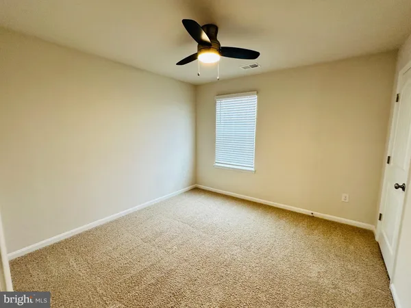 an empty room with a ceiling fan and window