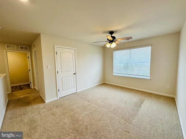 an empty room with windows and ceiling fan