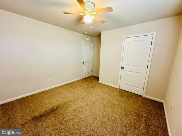 an empty room with a ceiling fan and carpet