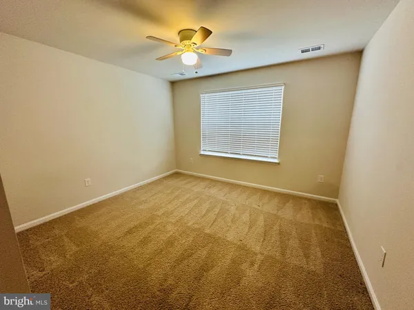 an empty room with a chandelier fan and windows