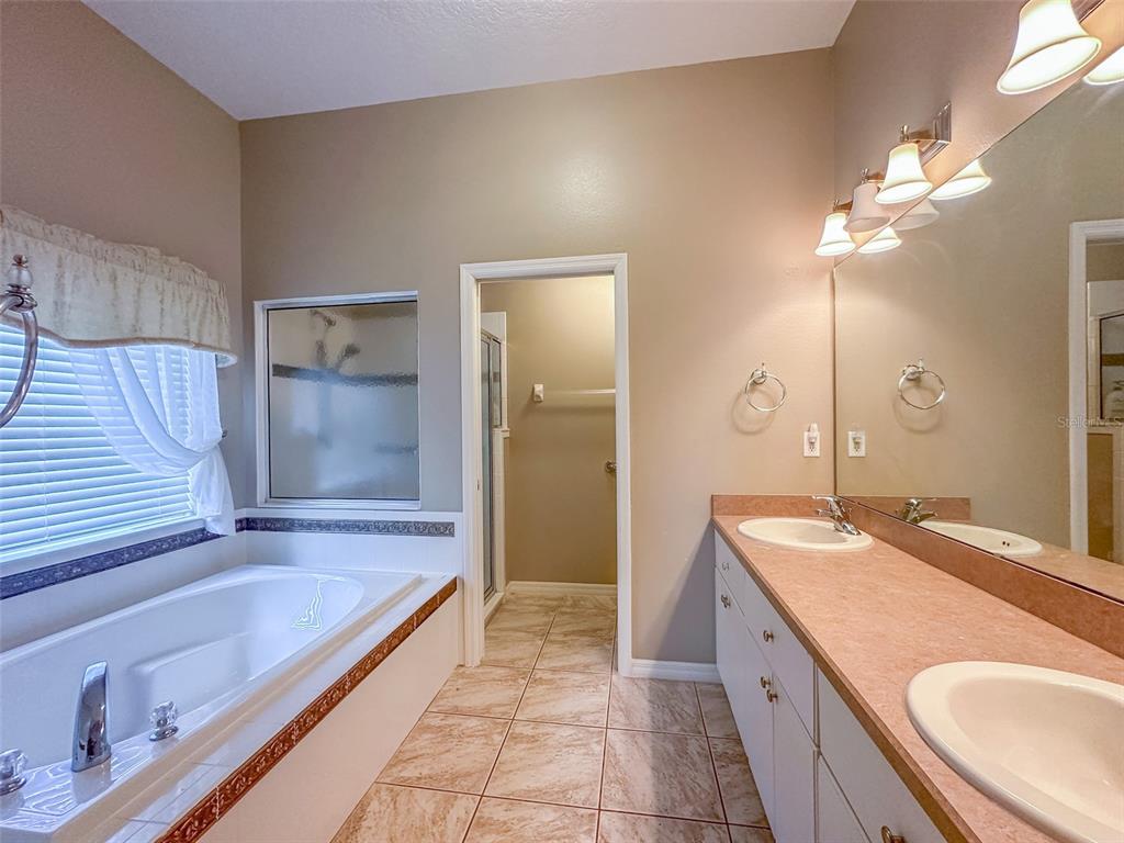 5300 Treasure View Way Leesburg, FL 34748 - Photo 12 of 47 a bathroom with a granite countertop double vanity sink a mirror and a bathtub