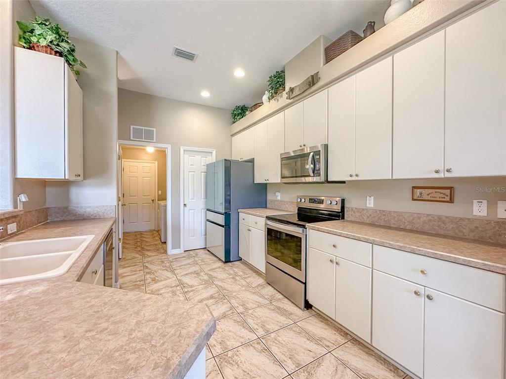 5300 Treasure View Way Leesburg, FL 34748 - Photo 7 of 47 a large kitchen with stainless steel appliances kitchen island granite countertop a refrigerator and cabinets