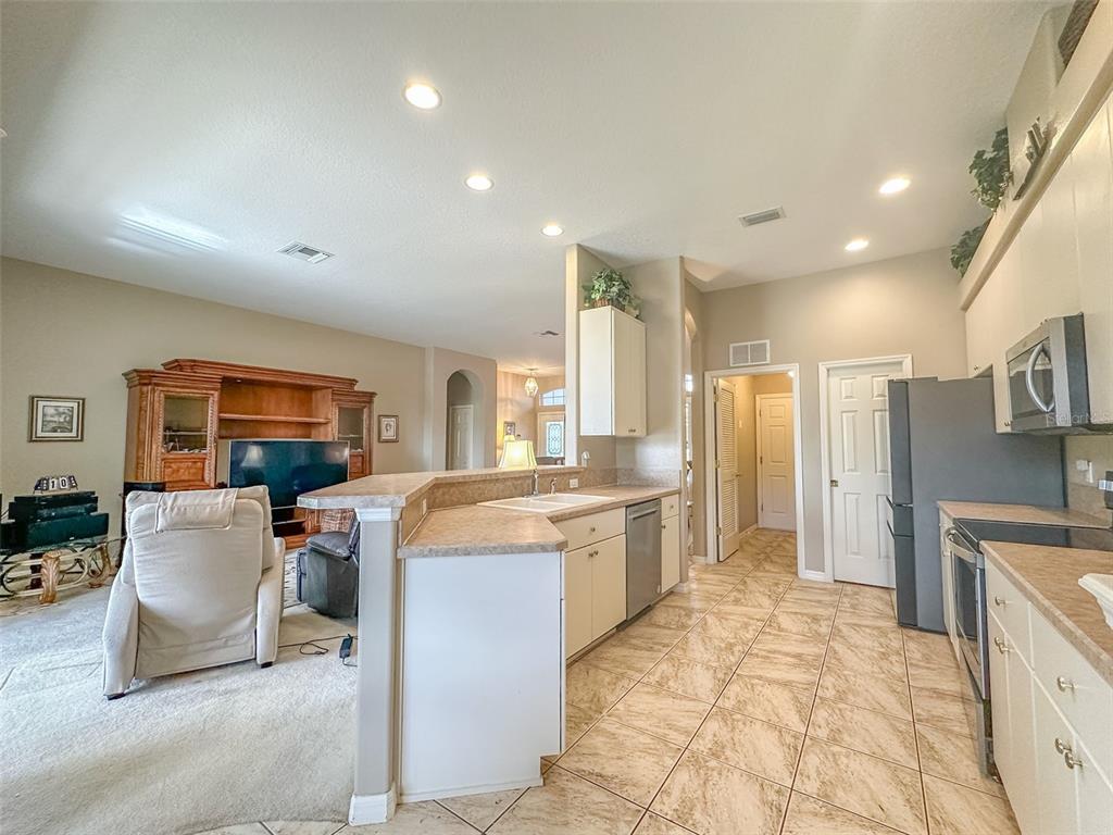5300 Treasure View Way Leesburg, FL 34748 - Photo 8 of 47 a large kitchen with stainless steel appliances a stove a sink dishwasher and a dining table with cabinets