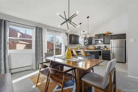a view of a dining room with furniture a kitchen and chandelier