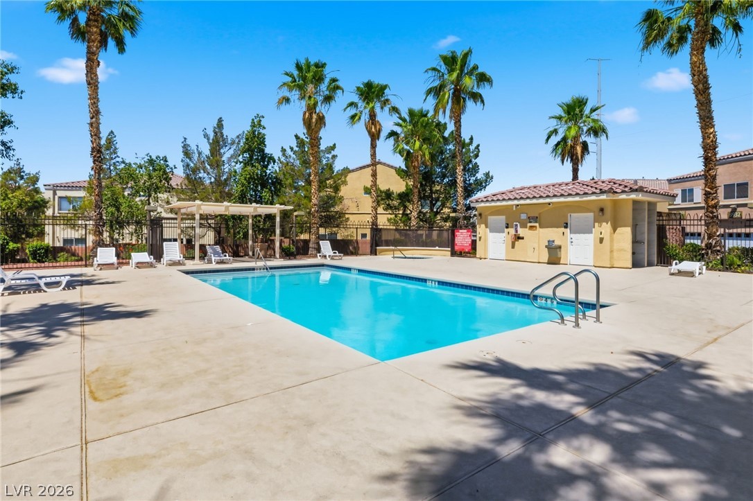 6312 Sandy Ridge Street, Unit 3102 North Las Vegas, NV 89081 - Photo 24 of 31 An inviting pool area with ample lounging space, framed by towering palm trees and a privacy fence.