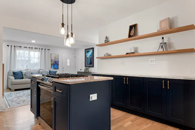 a kitchen with stainless steel appliances granite countertop a sink a stove and a wooden floors