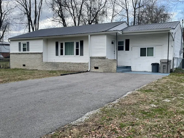 a view of a house with a yard and large tree
