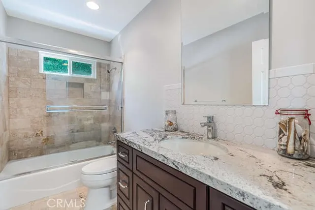 a bathroom with a granite countertop sink a toilet and shower