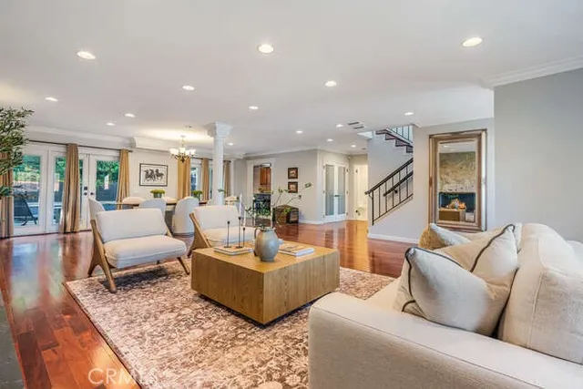 a living room with furniture kitchen view and a wooden floor