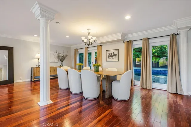 a dining room with wooden floor and large windows
