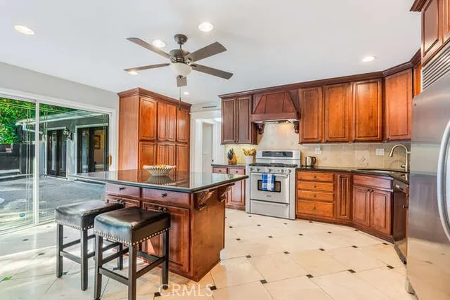 a kitchen with stainless steel appliances kitchen island granite countertop a stove top oven a sink a dining table and chairs with wooden floor